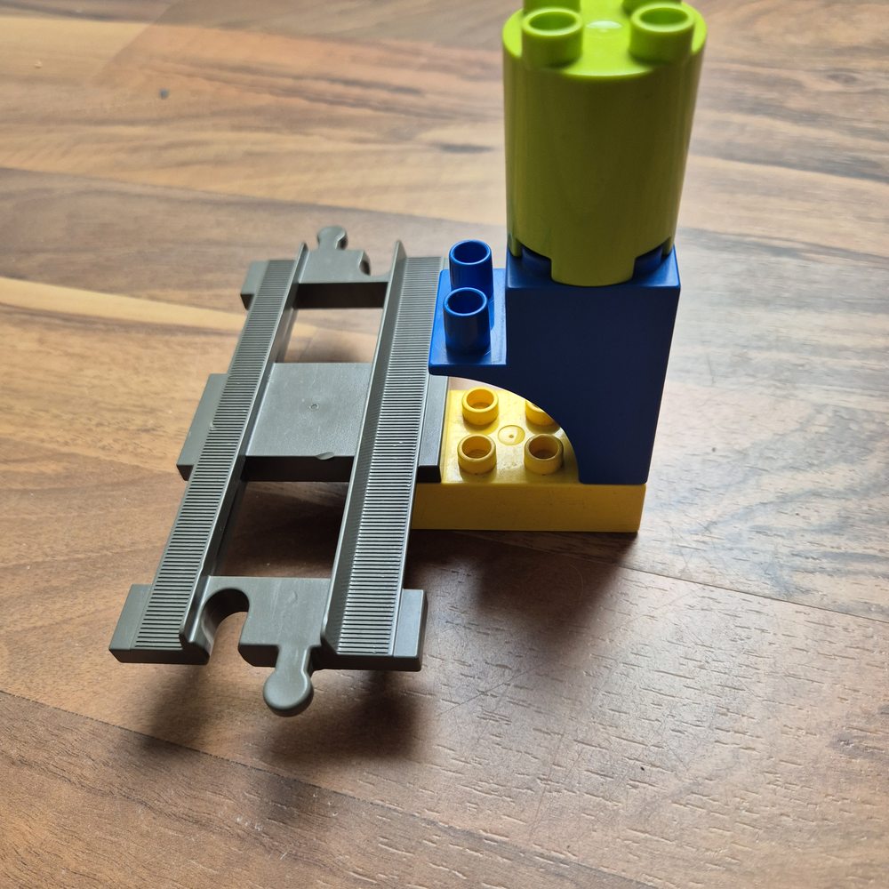 Duplo-Bausteine und ein Stück Zugschiene auf einem Holztisch